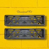Two black metal grates with geometric design on a yellow brick wall background. car registration frame plate